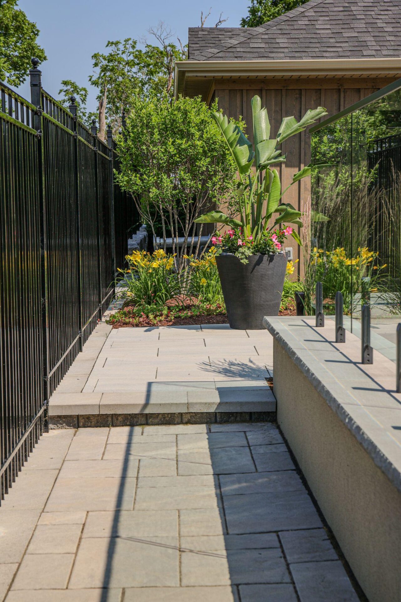 Large planter by a black fence with low-maintenance landscaping.