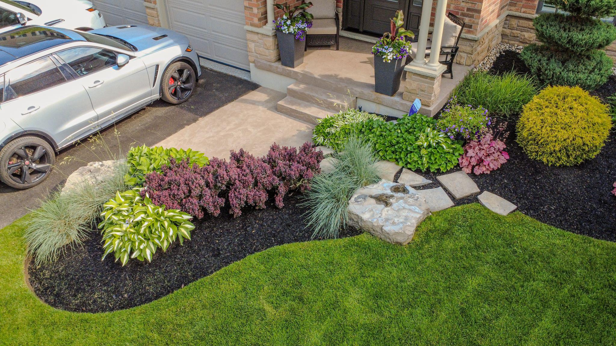 A parked car in front of a residential home maintained with landscaping services.