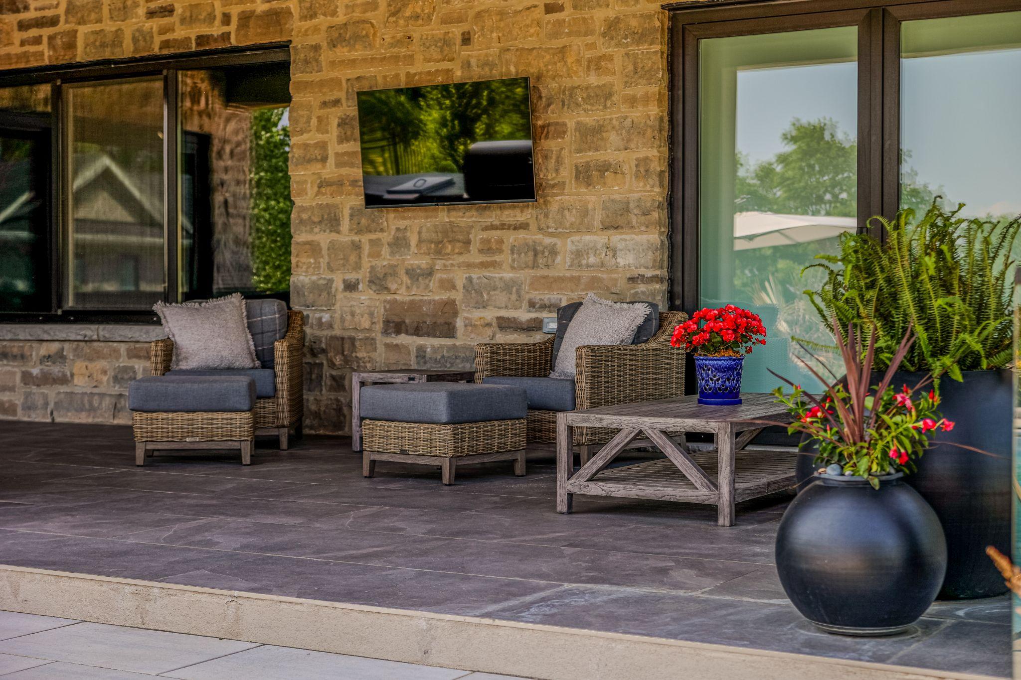 A patio with chairs and table featuring flowers.
