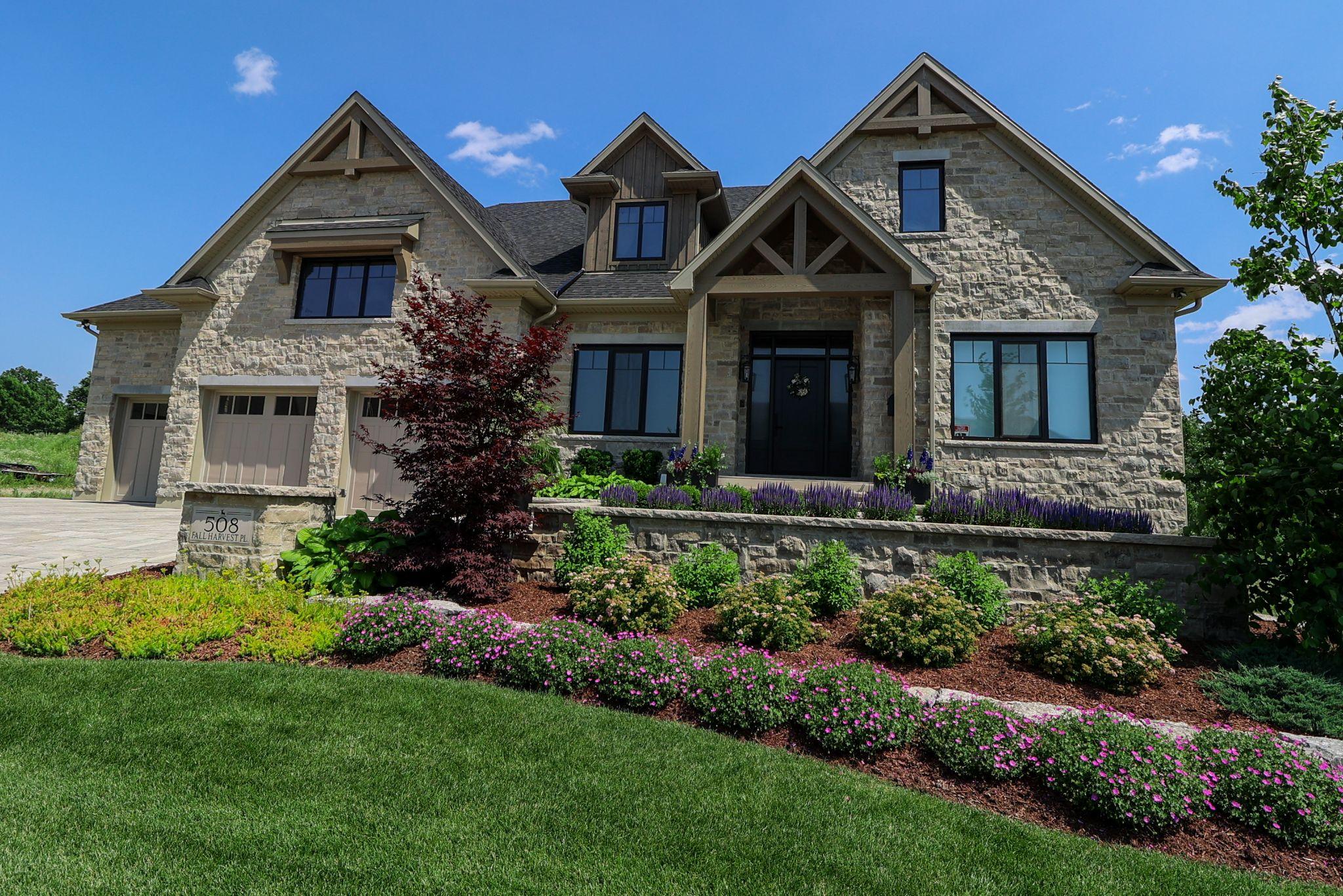 A stone house with a flower bed enhancing its front yard landscape.