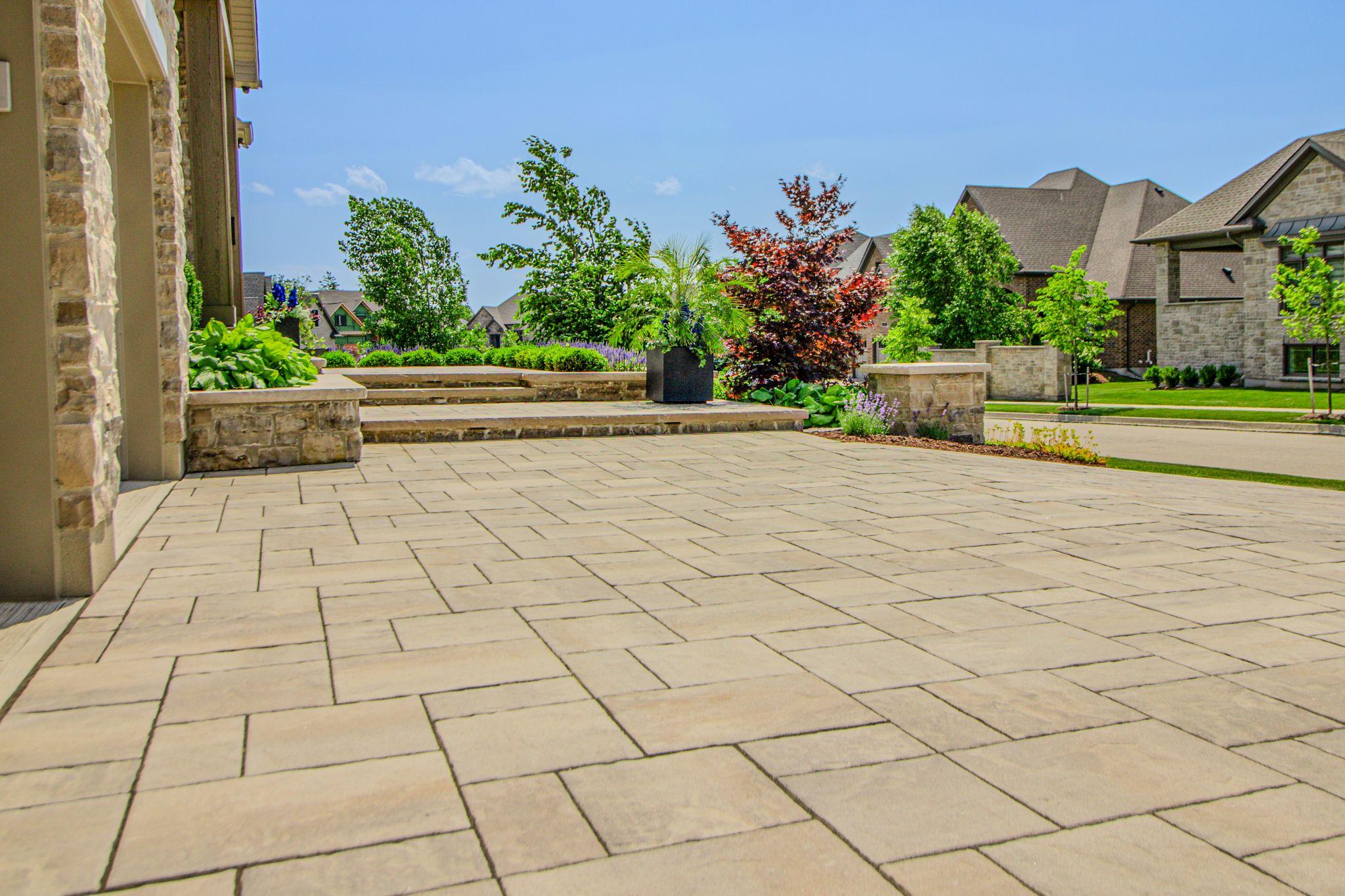 A brick patio with a stone bench and trees in a low-maintenance landscape.