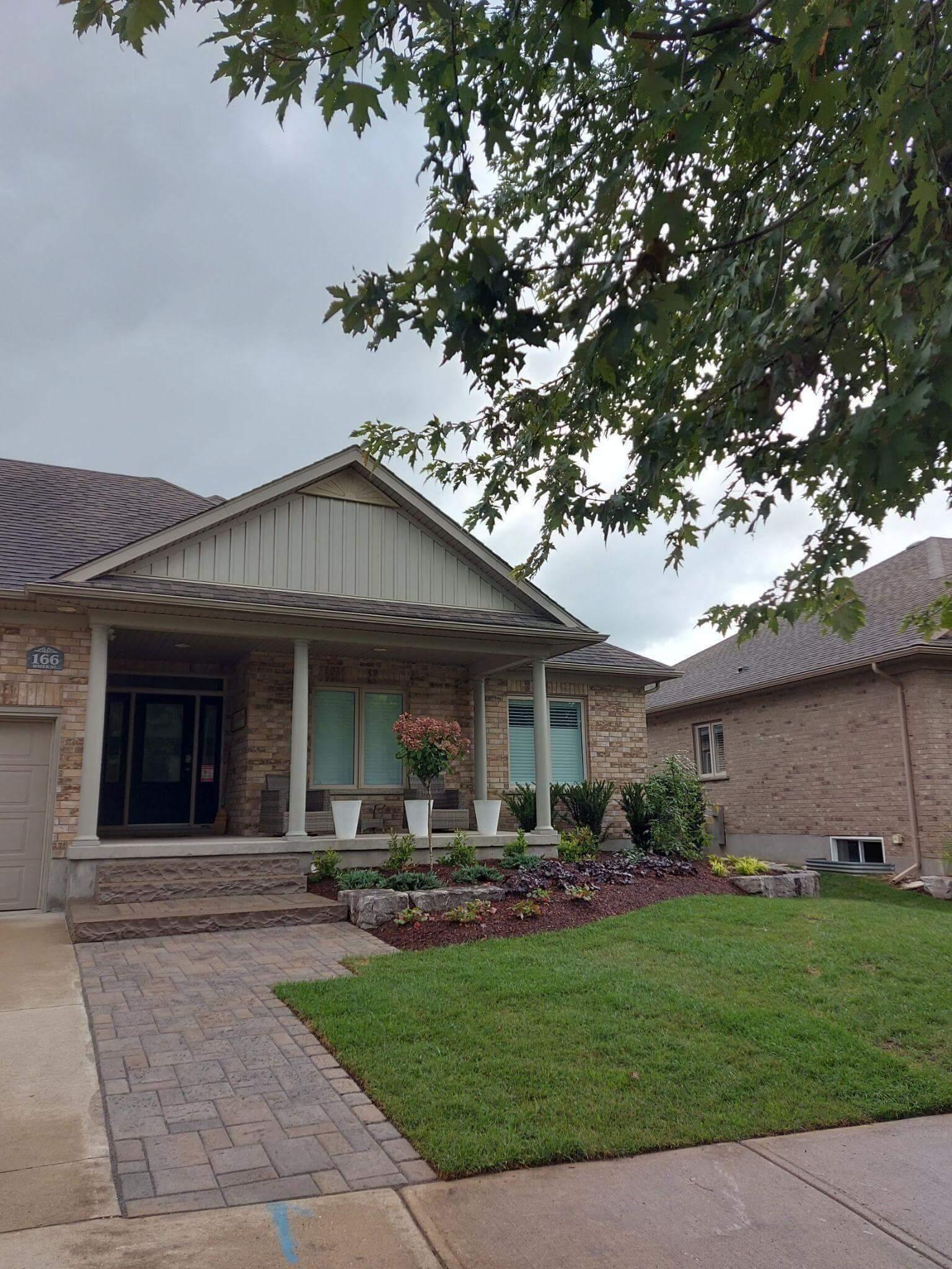 The front of a house using landscape design and build including a custom stone pathway and well-arranged plants.