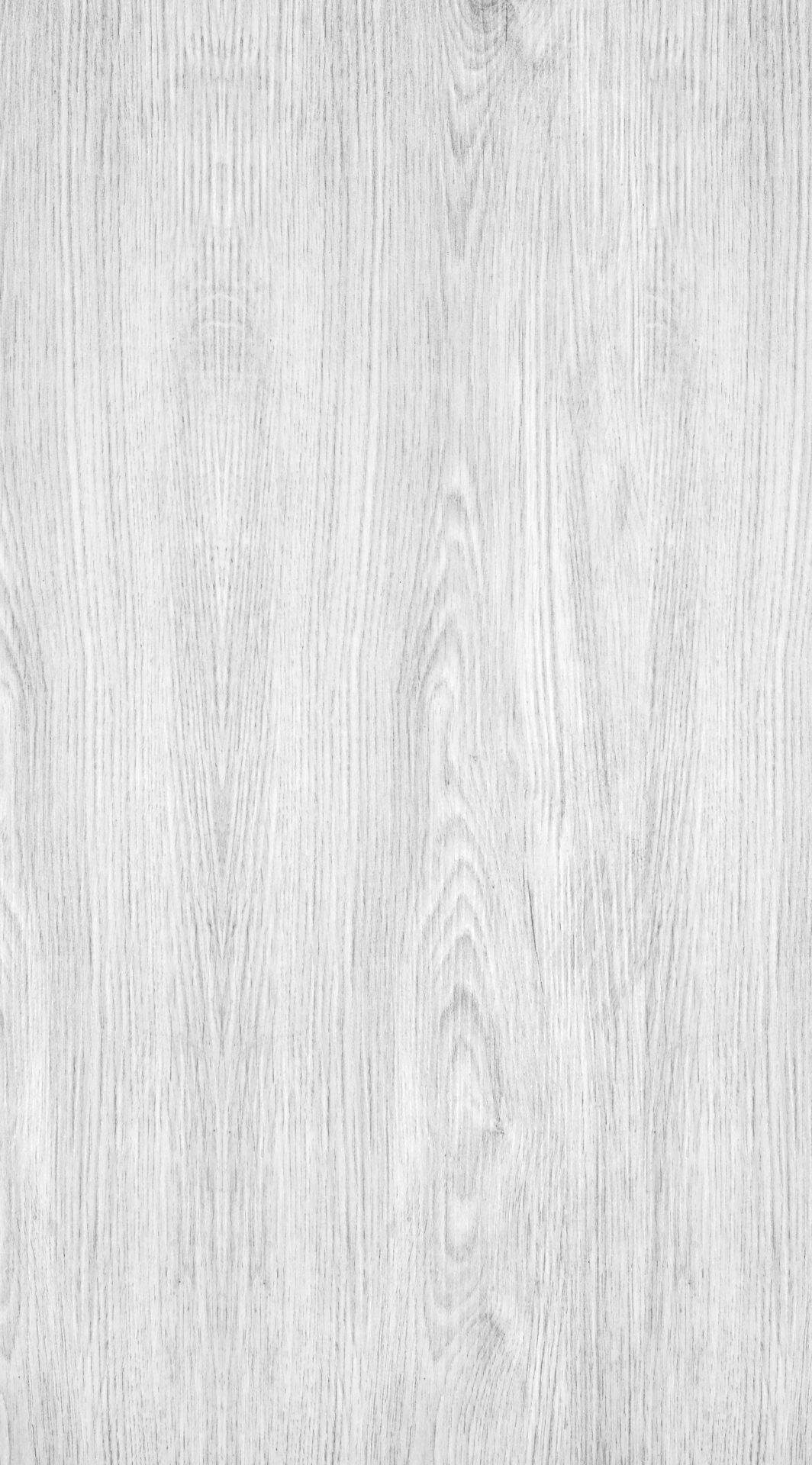 The image shows a close-up of a textured, light gray wooden surface with visible natural grain patterns and subtle variations.