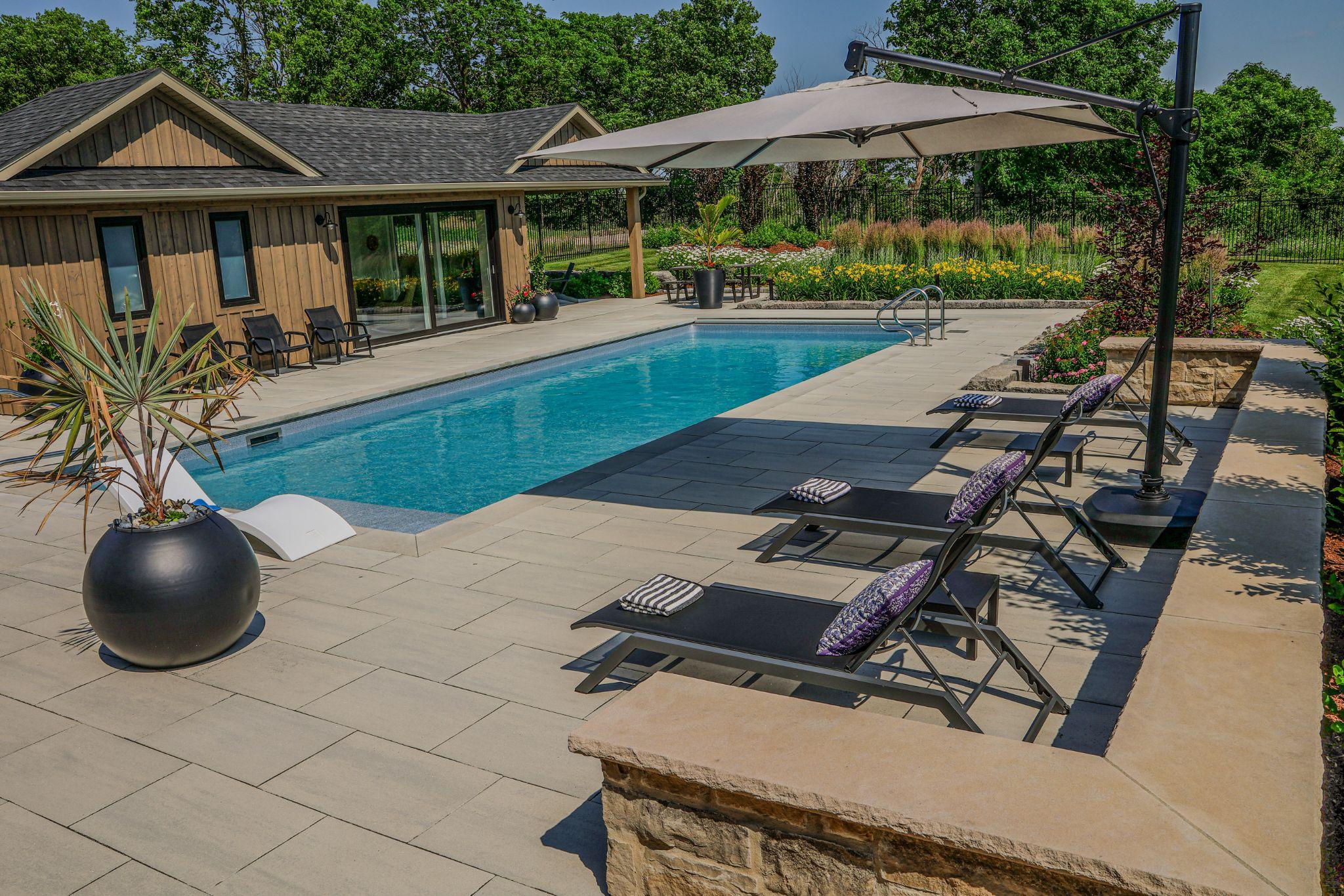 Back yard landscaping ideas using a swimming pool with lounge chairs to set the scene.
